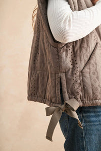 Beige quilted eyelet vest with lace crochet trim and bow tie closure