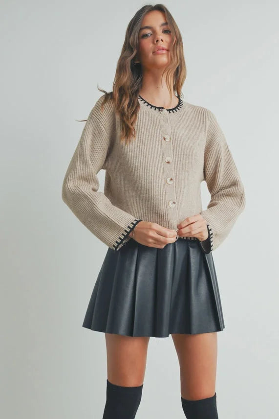 Beige ribbed crewneck cardigan sweater with black beaded trim and buttons