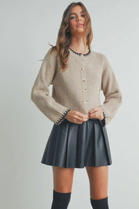 Beige ribbed crewneck cardigan sweater with black beaded trim and buttons