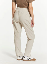 Beige straight-leg Supply Paige pants with elastic waistband and white Adidas sneakers