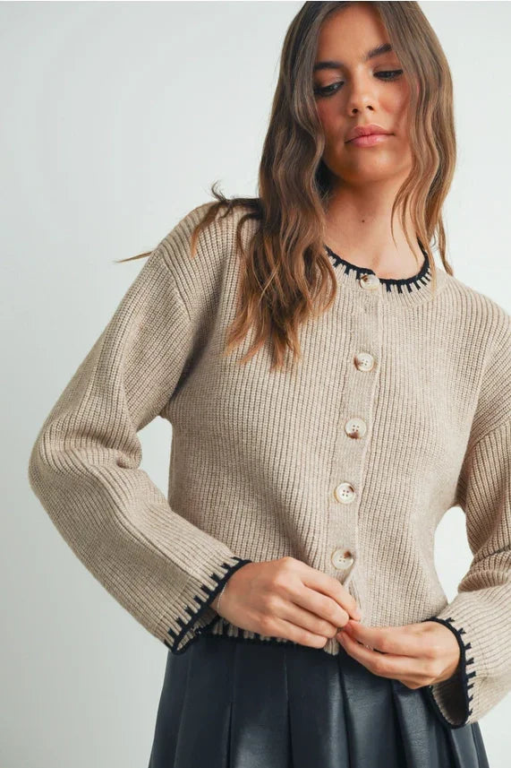 Beige textured crewneck cardigan sweater with black trim and buttons