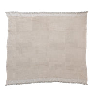 Beige cotton weave blanket featuring a waffle texture and fringe edges for a bohemian style