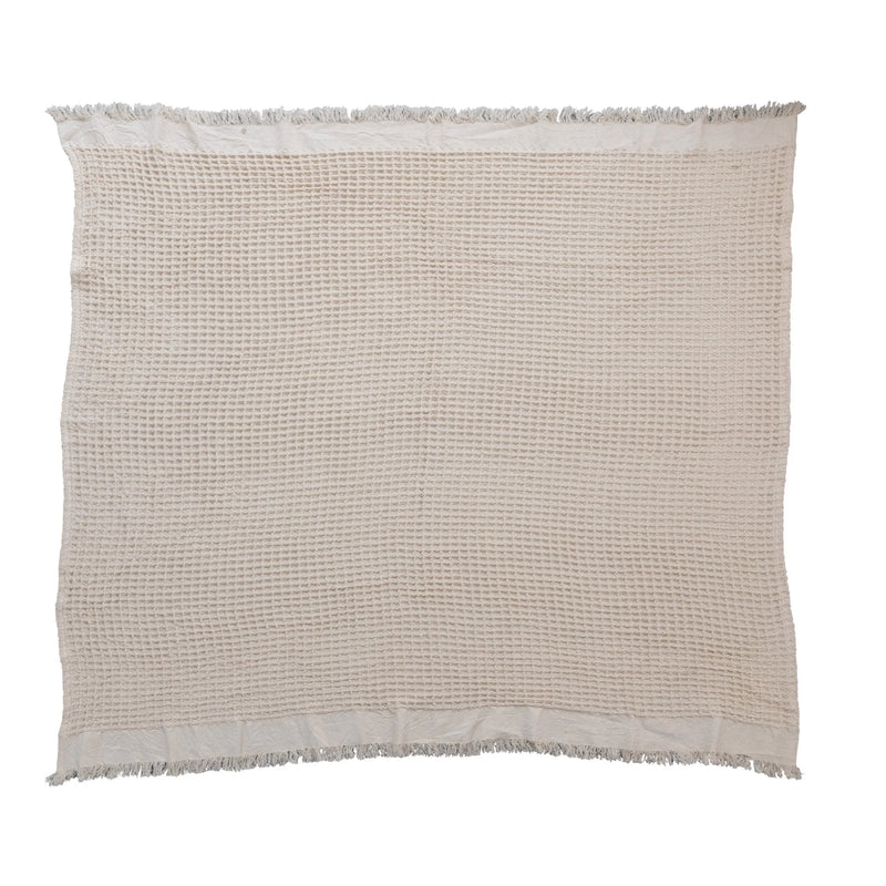 Beige cotton weave blanket featuring a waffle texture and fringe edges for a bohemian style