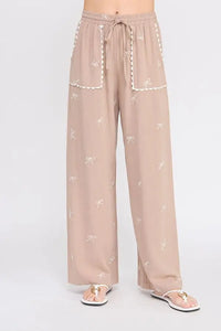 Beige embroidered linen pants with bow pattern and scallop trim, stylish linen pants