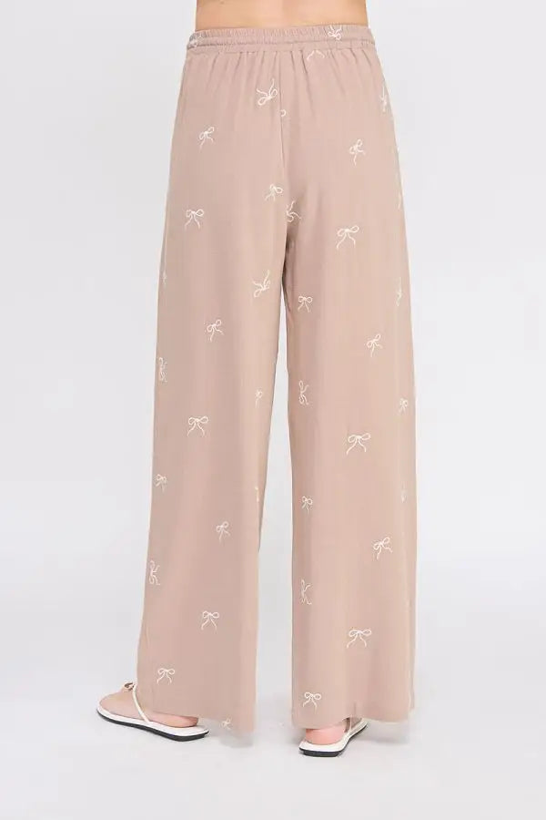 Beige embroidered linen pants with bow pattern and scallop trim for a stylish look