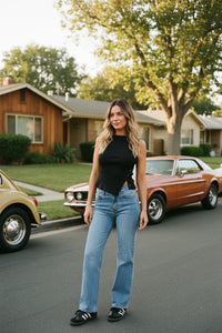 Mid rise straight leg denim jean with black high-neck bodysuit and white Adidas sneakers