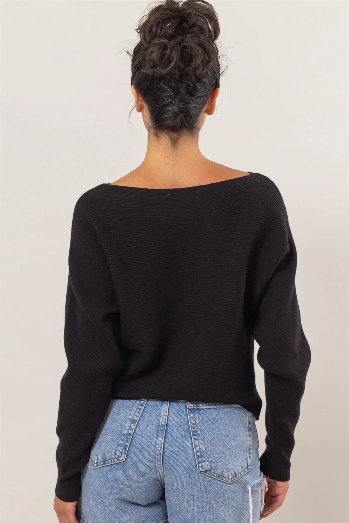 Black knit long sleeve sweater with boat neckline paired with light wash jeans