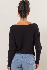 Black knit long sleeve sweater with boat neckline paired with light wash jeans