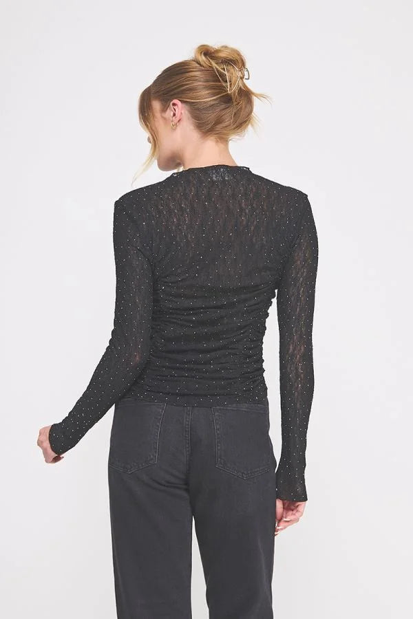 Black long-sleeved top with sheer textured fabric, glittery speckles, and scrunched princess seams