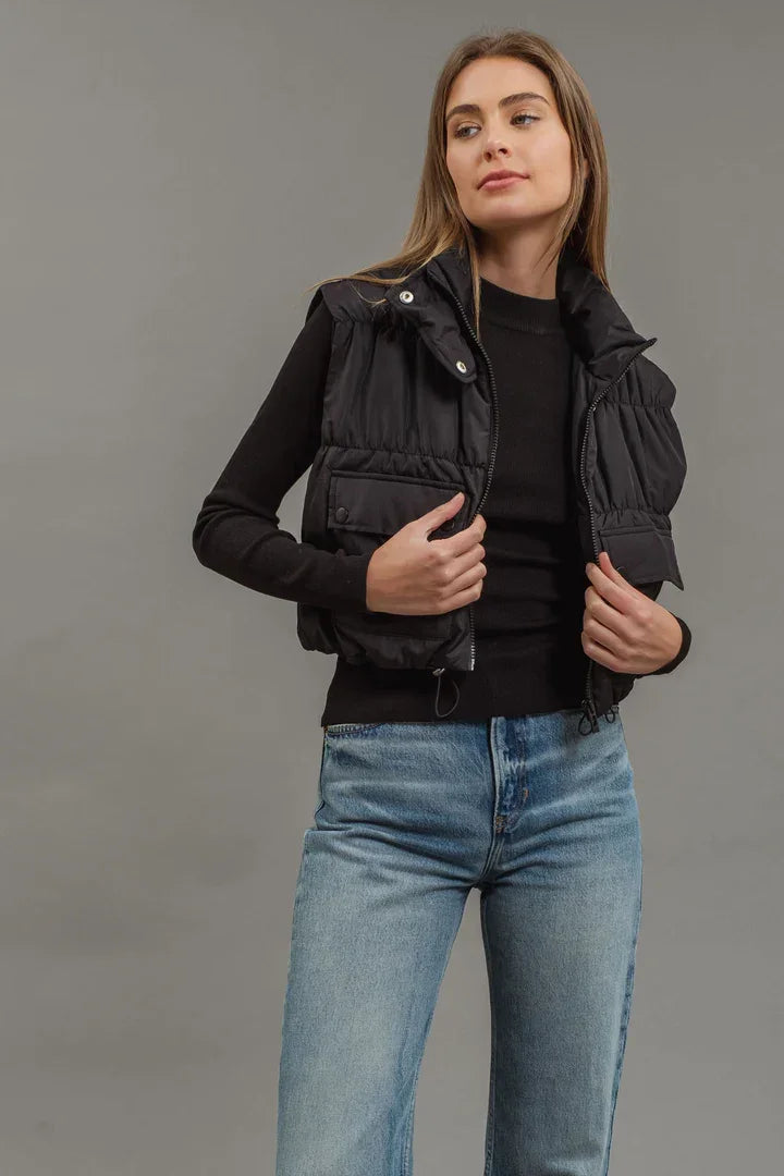 Black puffer vest layered over dark top and blue jeans, ideal for women’s boho chic clothing