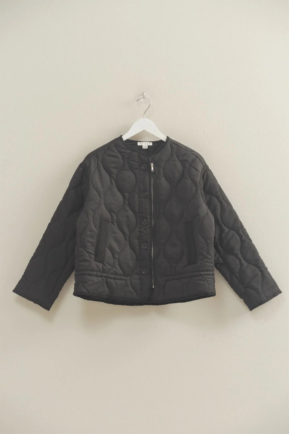 Black quilted peplum outerwear jacket with textured pattern and button closure