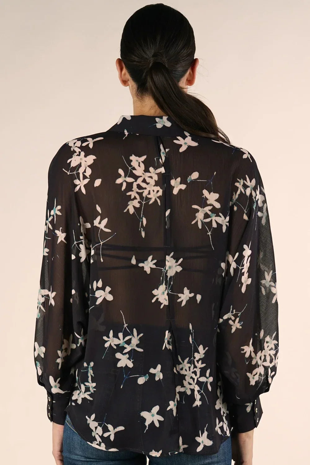 Black sheer long sleeve floral blouse with long sleeve button design worn by a woman