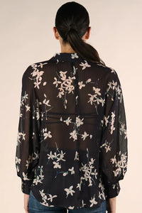 Black sheer long sleeve floral blouse with long sleeve button design worn by a woman