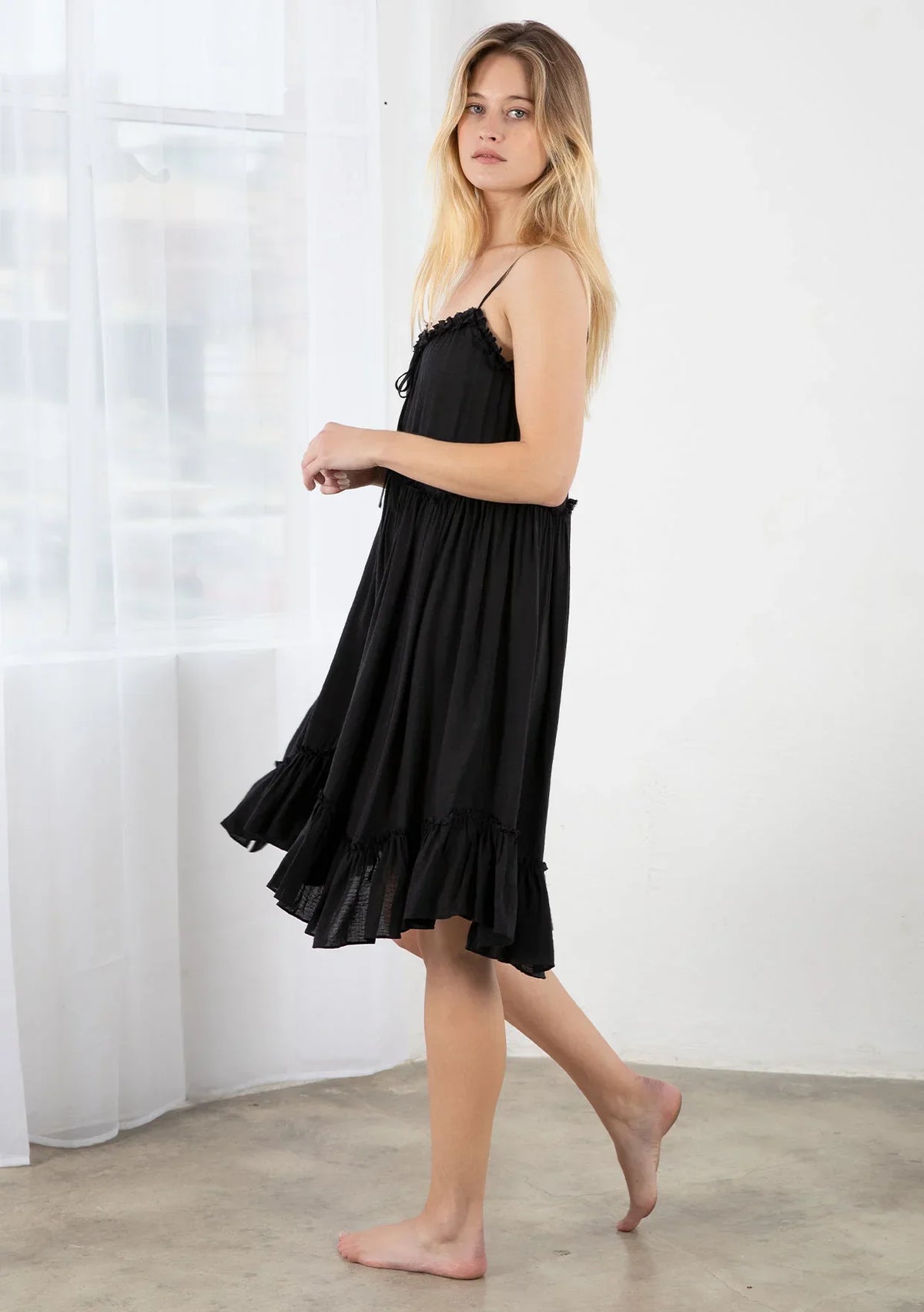 Black spaghetti-strap mini dress with ruffled hem, perfect for trendy bohemian style