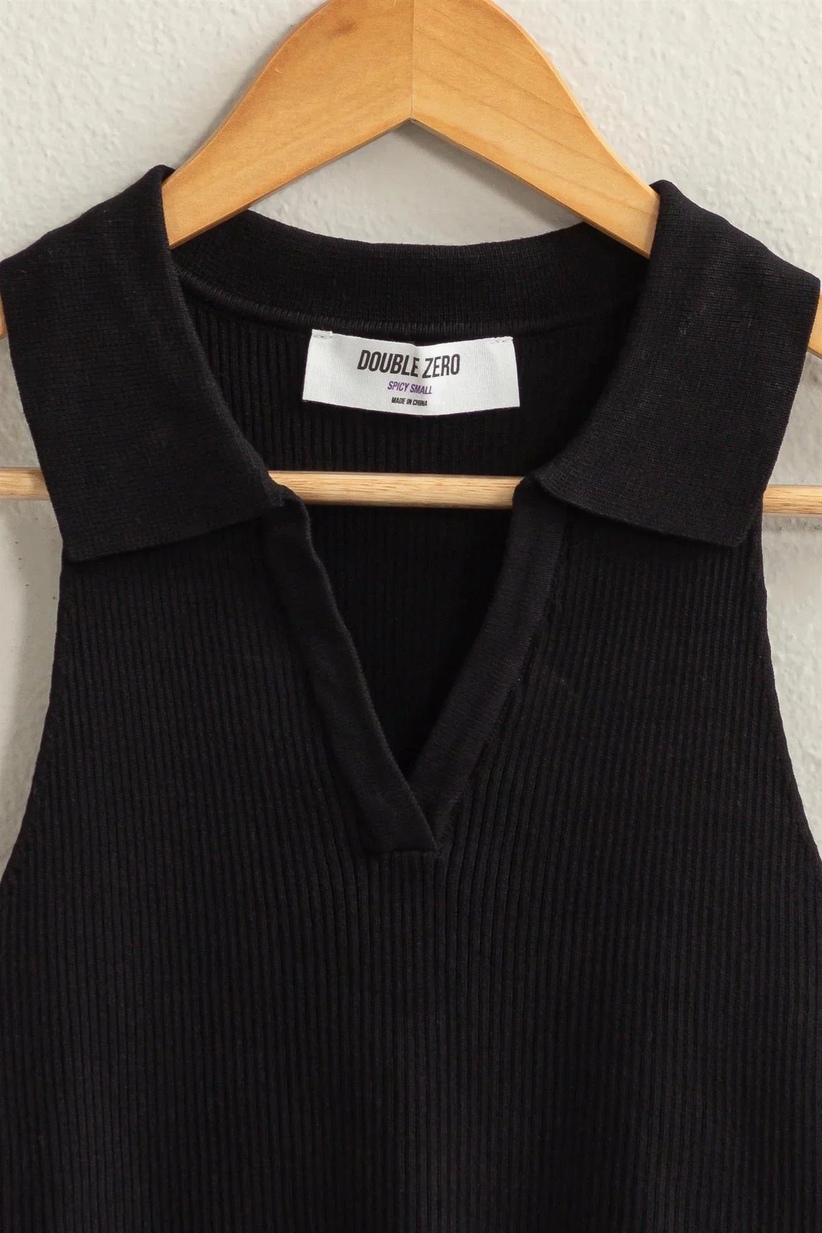 Black sleeveless collared crop knit top featuring a collar and a white label