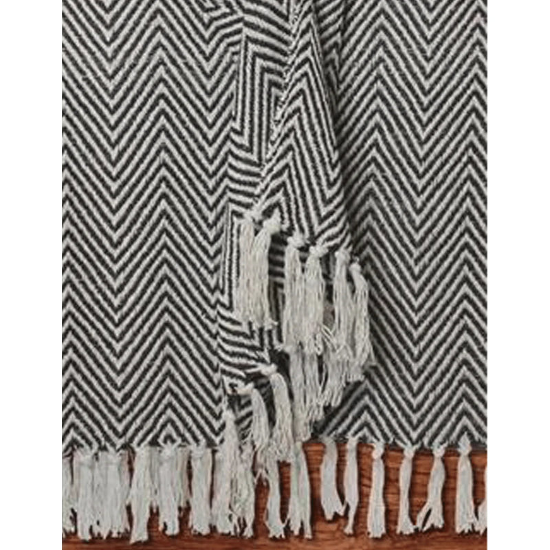 Black and white Ecru Woven Chevron Throw with fringes on wooden floor