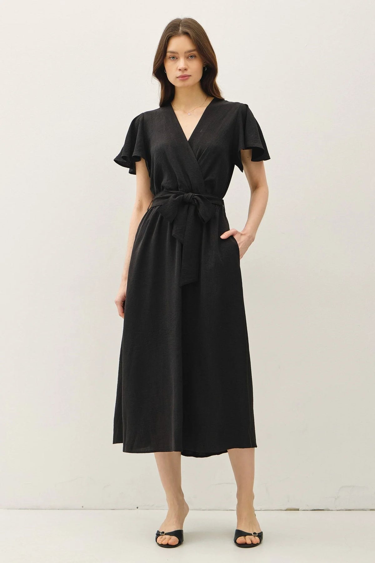 Black wrap midi dress featuring ruffle cap sleeves, v neck, and tie waist design