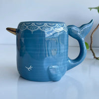 Blue ceramic narwhal folk art mug with decorative patterns and hand sculpted narwhal design