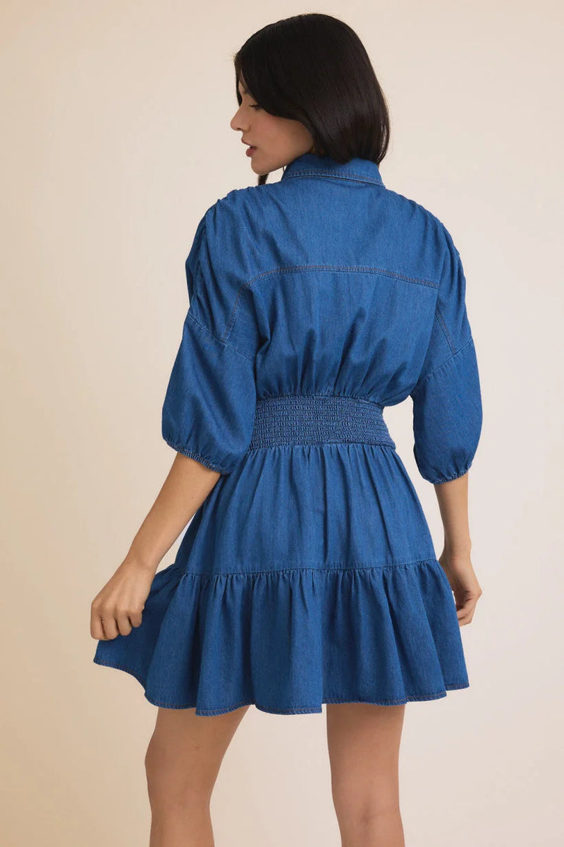 Blue denim 3/4 sleeve mini dress with puff sleeves, smocked waist, and ruffled hem