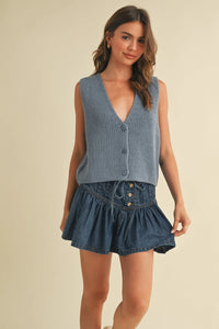 Blue denim mini skirt with ruffled hem on sleeveless vest sweater