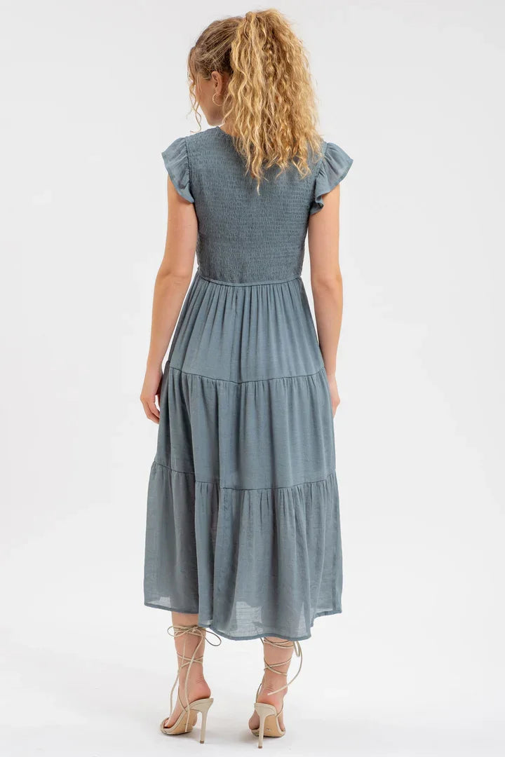 Blue-gray smocked tiered midi dress with flutter sleeves, viewed from behind