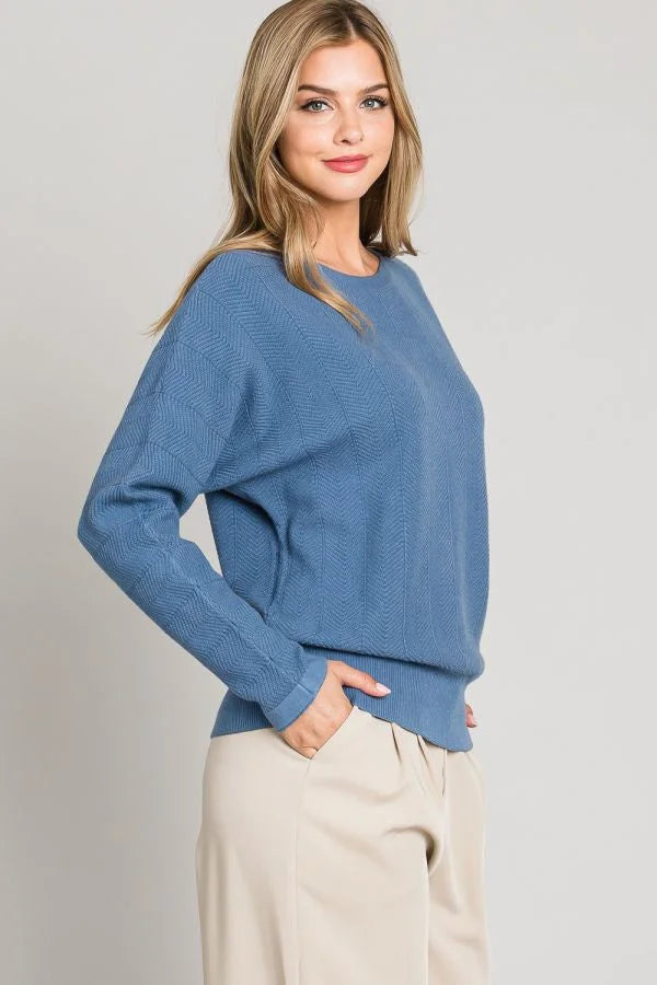 Blue long-sleeved sweater featuring a soft chevron pattern pullover style worn by a woman