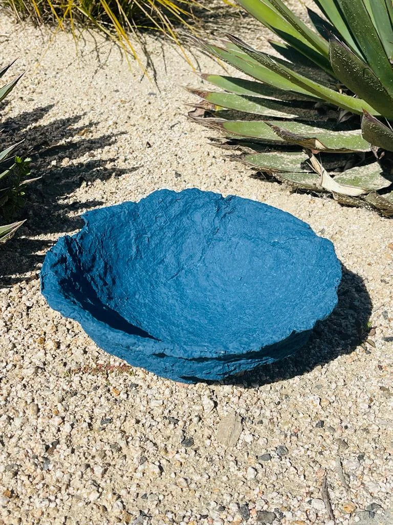 Blue rock in the desert beside a decorative handmade paper mache bowl