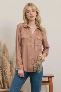 Blonde woman wearing a blush-colored striped button shirt with front pockets