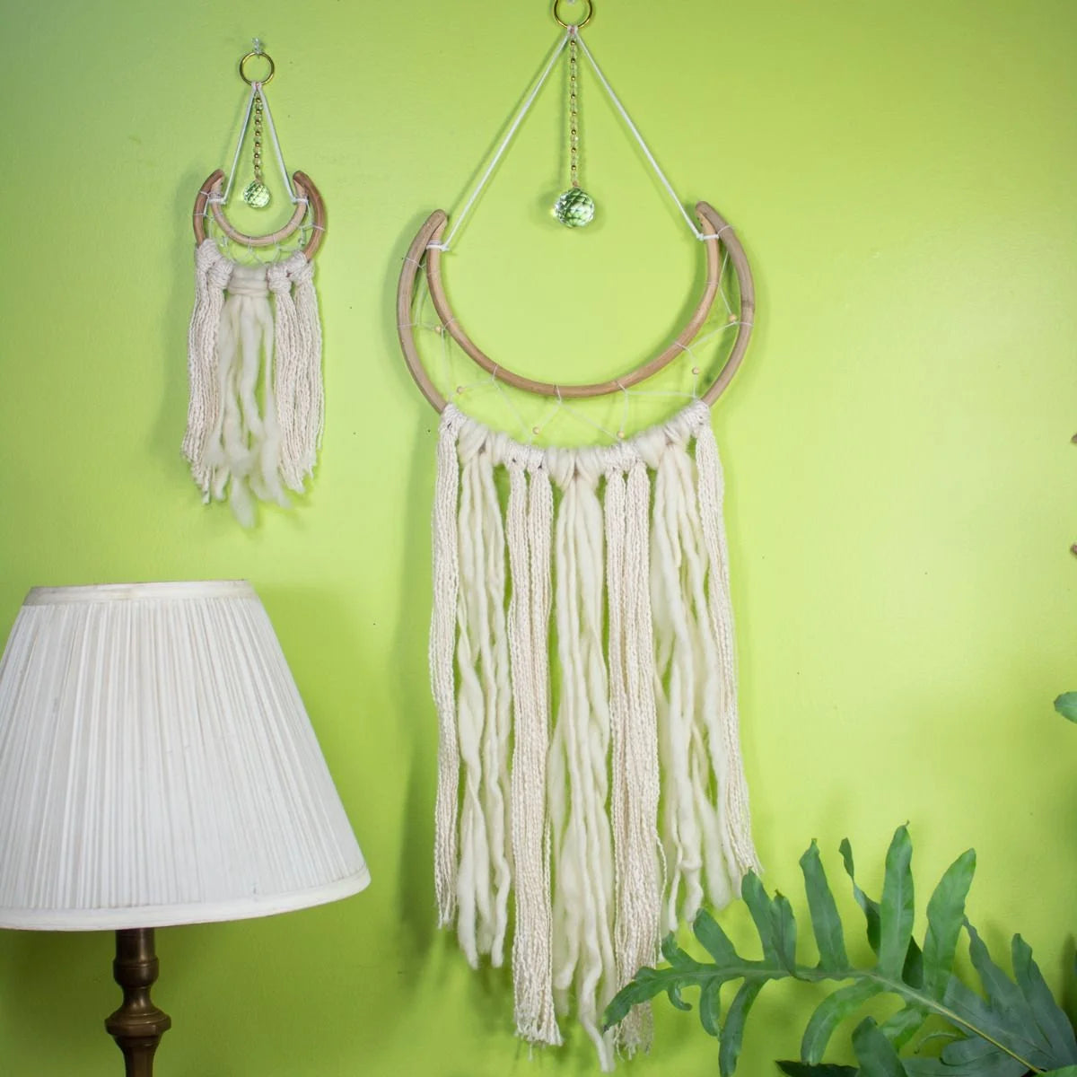 Boho-style wall decor featuring white yarn tassels on a wooden crescent frame