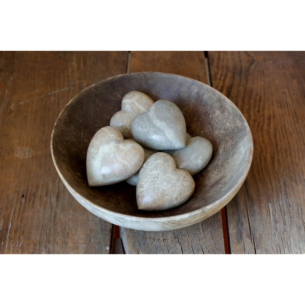 A bowl of white rocks on a wooden table for the Soapstone Heart boho decor