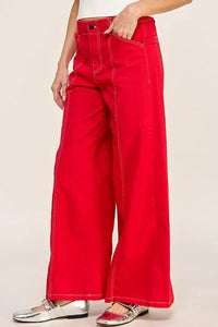 Bright red high rise wide leg denim jeans with contrast stitching and metallic sneakers