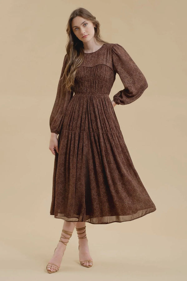 Brown long-sleeved maxi dress featuring a gathered waist and flowy skirt design