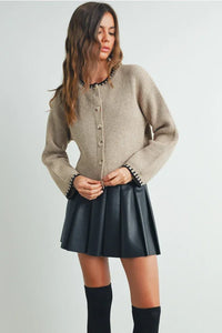 Brown crewneck cardigan sweater with ribbed design, black buttons, faux leather skirt, knee-high boots