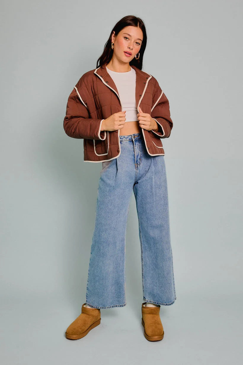 Brown sherpa-trimmed drop shoulder high collared quilt jacket with light blue jeans and tan boots