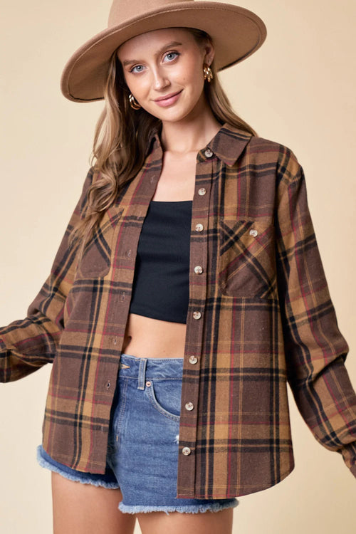 Brown and tan plaid flannel shirt layered over a black crop top and denim shorts from Shop Daisy