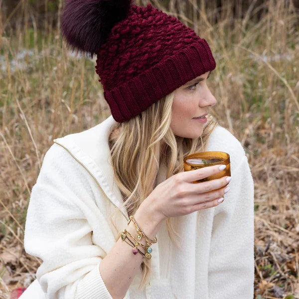 Burgundy cable-knit beanie with fur pom-pom for women’s boho chic style