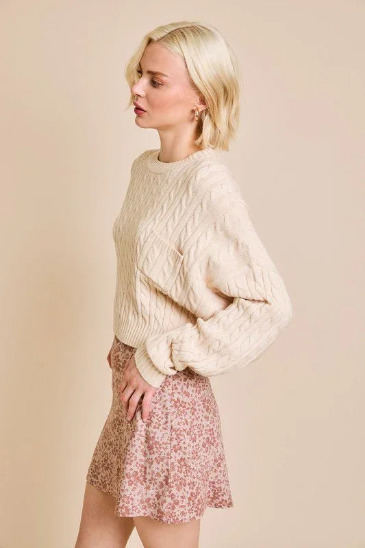 Cable-knit cream dolman sleeve cable sweater paired with a pink floral mini skirt