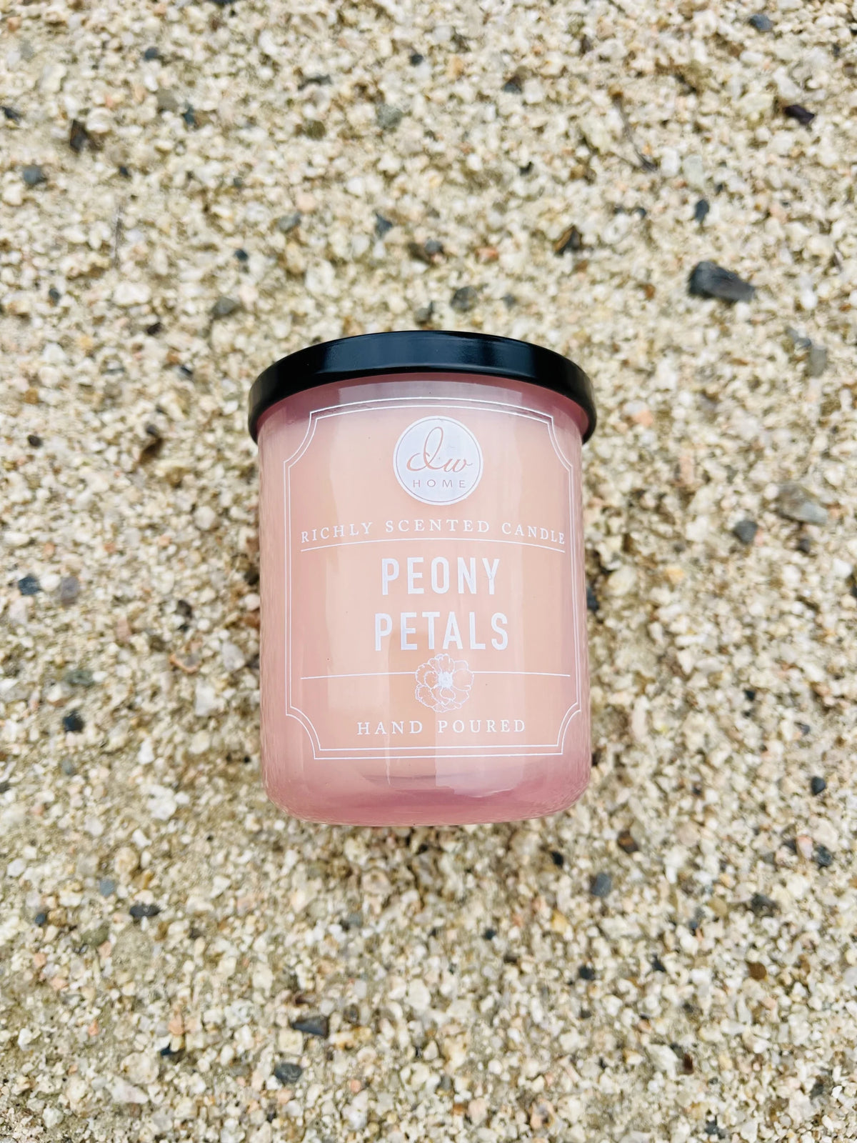 Candle on gravel ground showcasing Peony Petals Mini Candle design and elegance