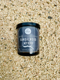 Sandalwood Myrrh Mini Candle placed on a sandy beach for a serene ambiance