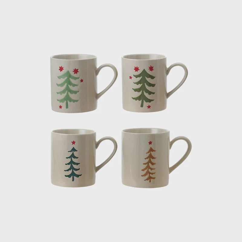 Holiday hand painted stoneware mug featuring ceramic Christmas tree design with green trees and red stars on a cream background