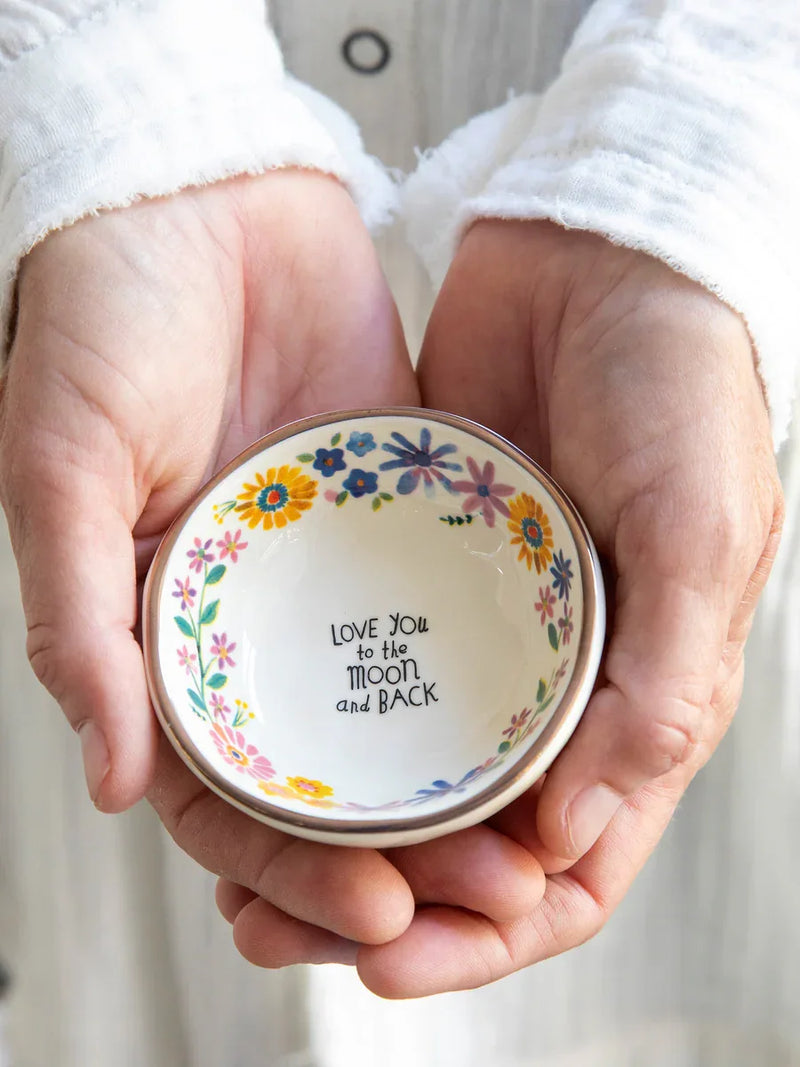 Ceramic trinket bowl with floral border and heartfelt message in hands, boho style