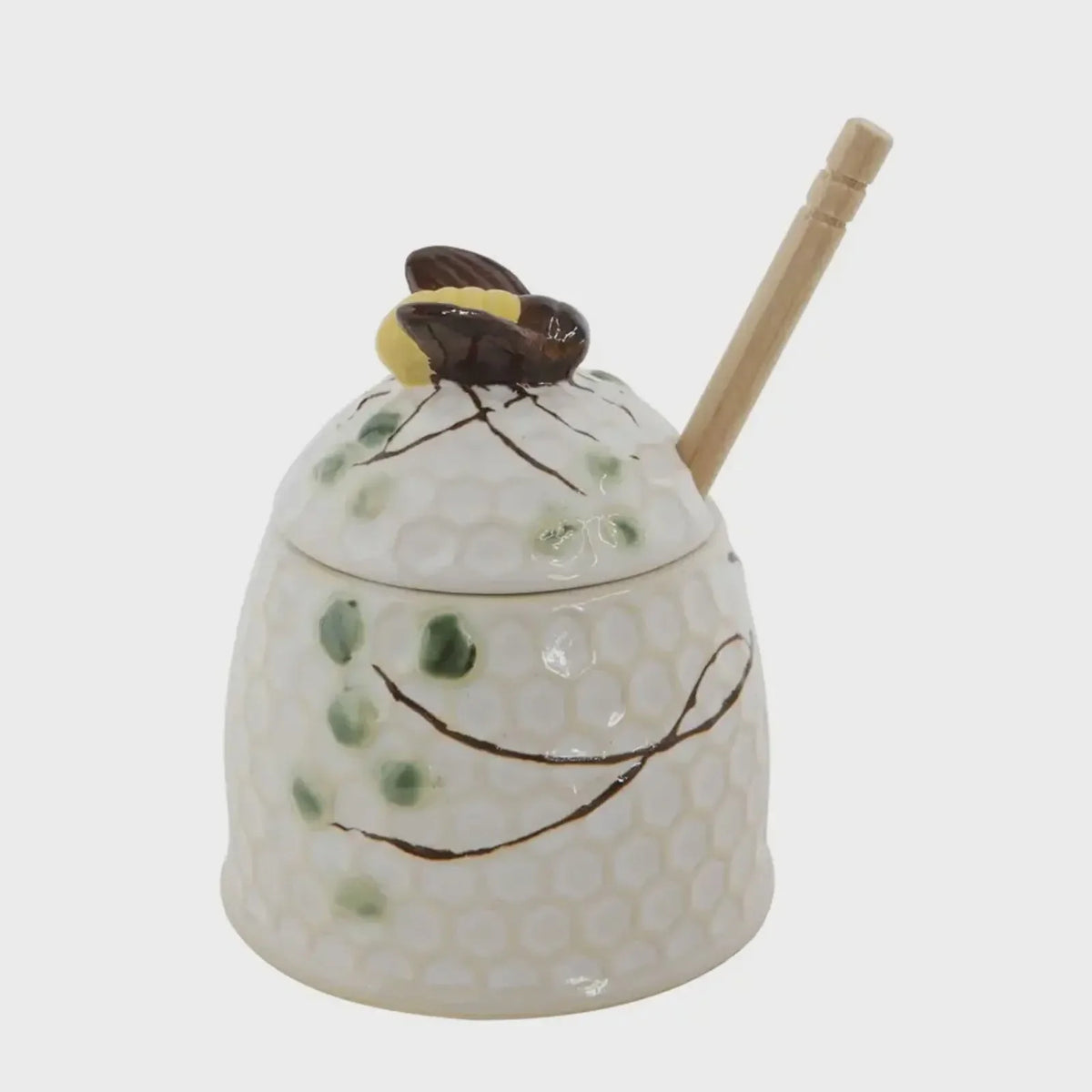 Hand painted honey jar with bee-shaped lid and wooden honey dipper for natural sweetness