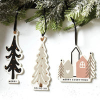 Colorful holiday ornaments in a gift box featuring tree and house shapes with merry Christmas messages