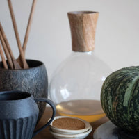 Clear glass carafe with wooden stopper in a stoneware mini bowl for stylish serving