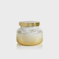 Volcano Glimmer Signature Candle in a clear glass jar with a golden base and lid