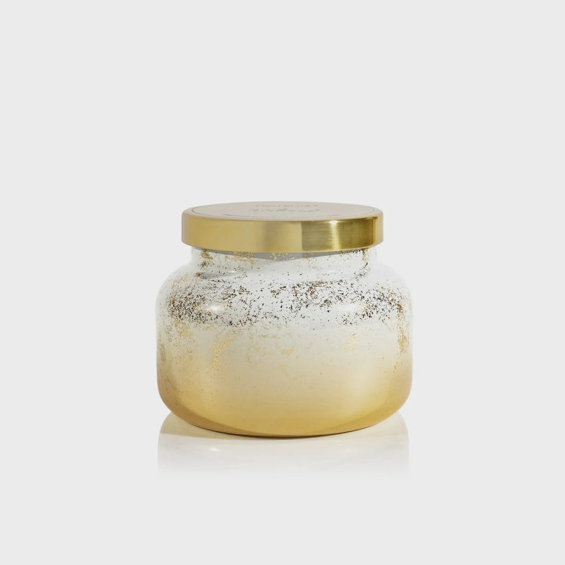 Volcano Glimmer Signature Candle in a clear glass jar with a golden base and lid