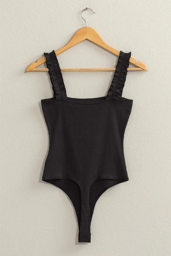 Close-up of a black Ribbed Ruffle Strap Bodysuit on a hanger showcasing its elegant design