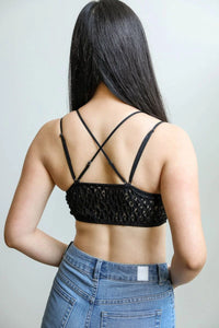 Close-up of a woman in a black padded crochet lace longline bralette and jeans