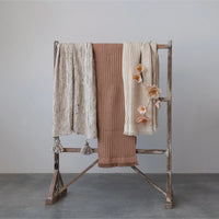 Clothing rack displaying various textured towels and a Natural Cotton Waffle Weave Bohemian Blanket