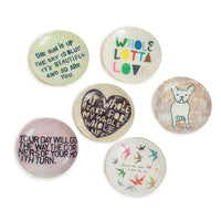 Decorative circular buttons featuring quotes and illustrations on Decoupage Jewelry Plate